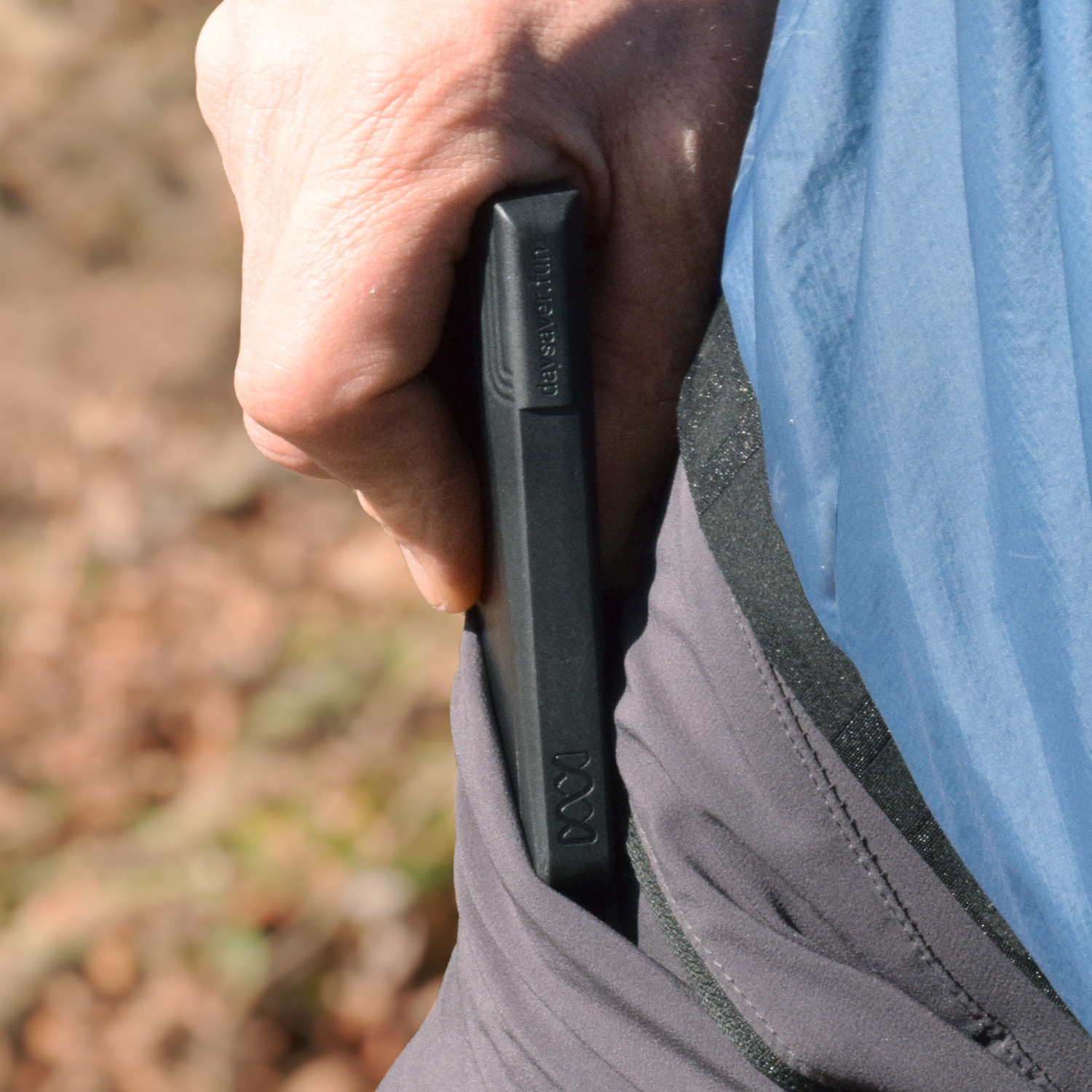 Person holding a black phone case with a blurred natural background
