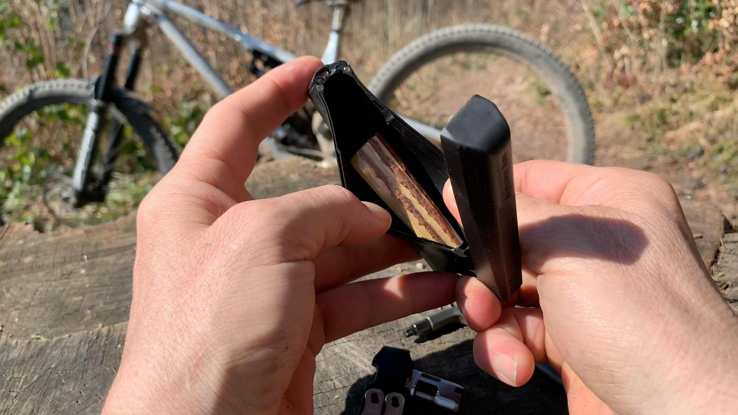 Person holding a bicycle chain in front of a bike outdoors